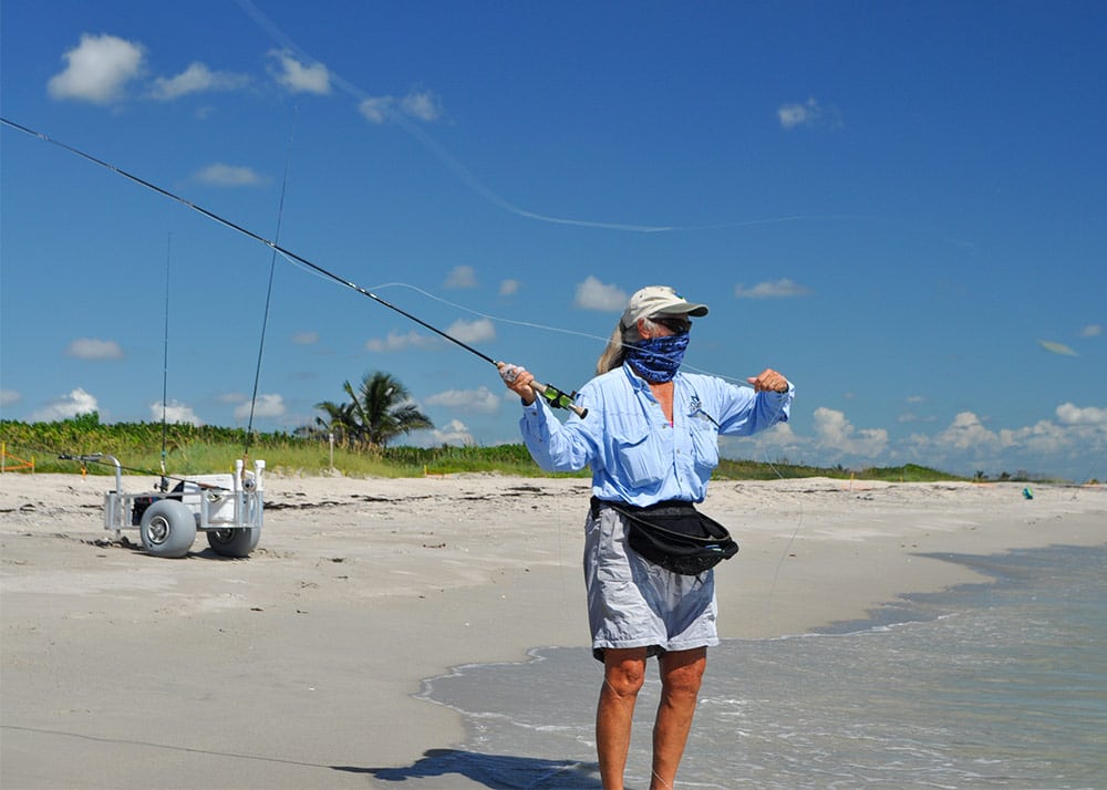 A shoreline with fishing rods on the ground and a nice sunny water