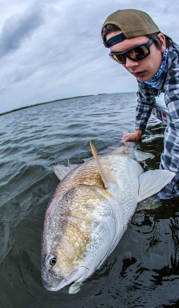 Young angler admires a Louisiana bull redfish boatside