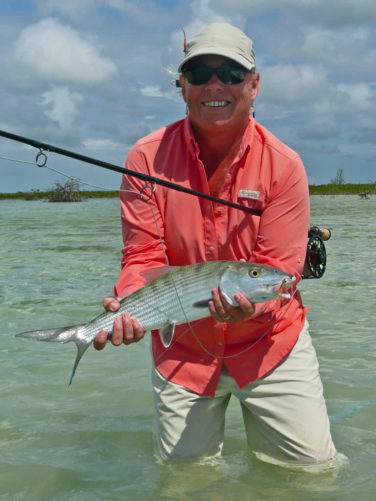 Mary Raulerson lifts her first Bahamain bonefish caught on fly for a quick photo.