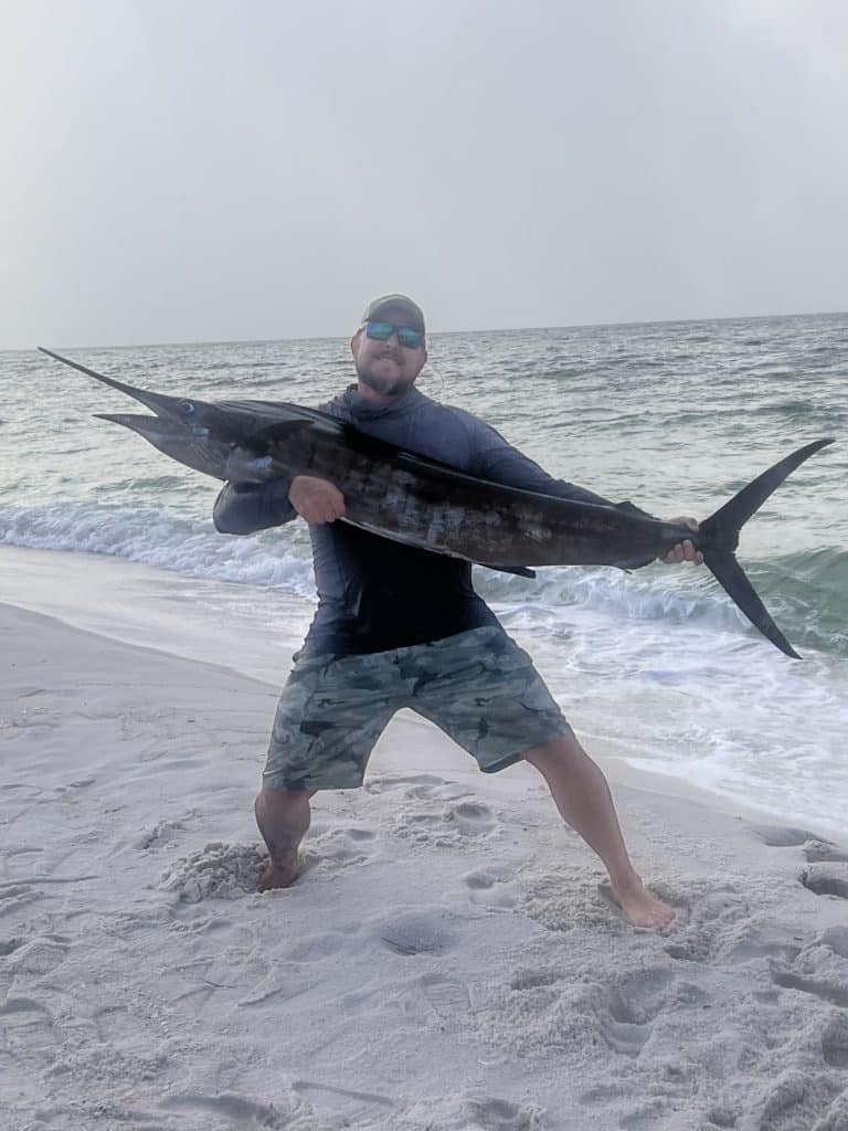 holding sailfish on beach