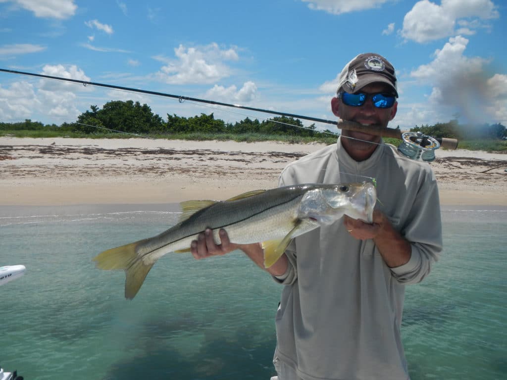 Angler holding up a snook caught while fly fishing