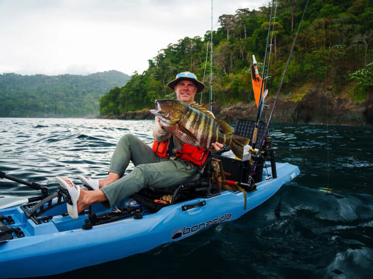 Angler holding up fish while kayaking