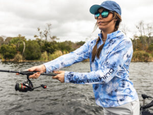 Angler casting while wearing a Huk fishing hoodie.