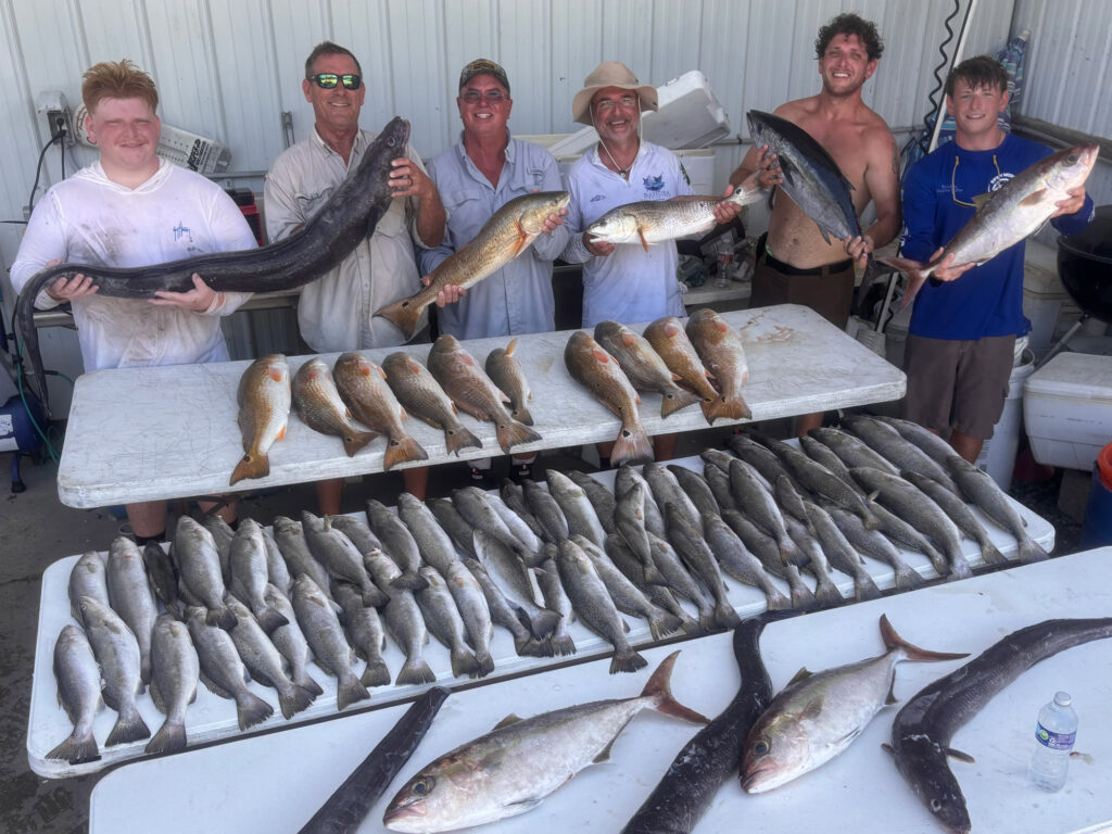 Anglers with the Mississippi record conger eel and a pile of other fish.