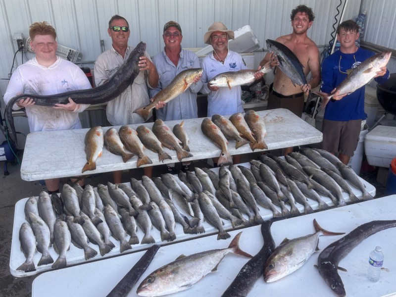 Anglers with the Mississippi record conger eel and a pile of other fish.